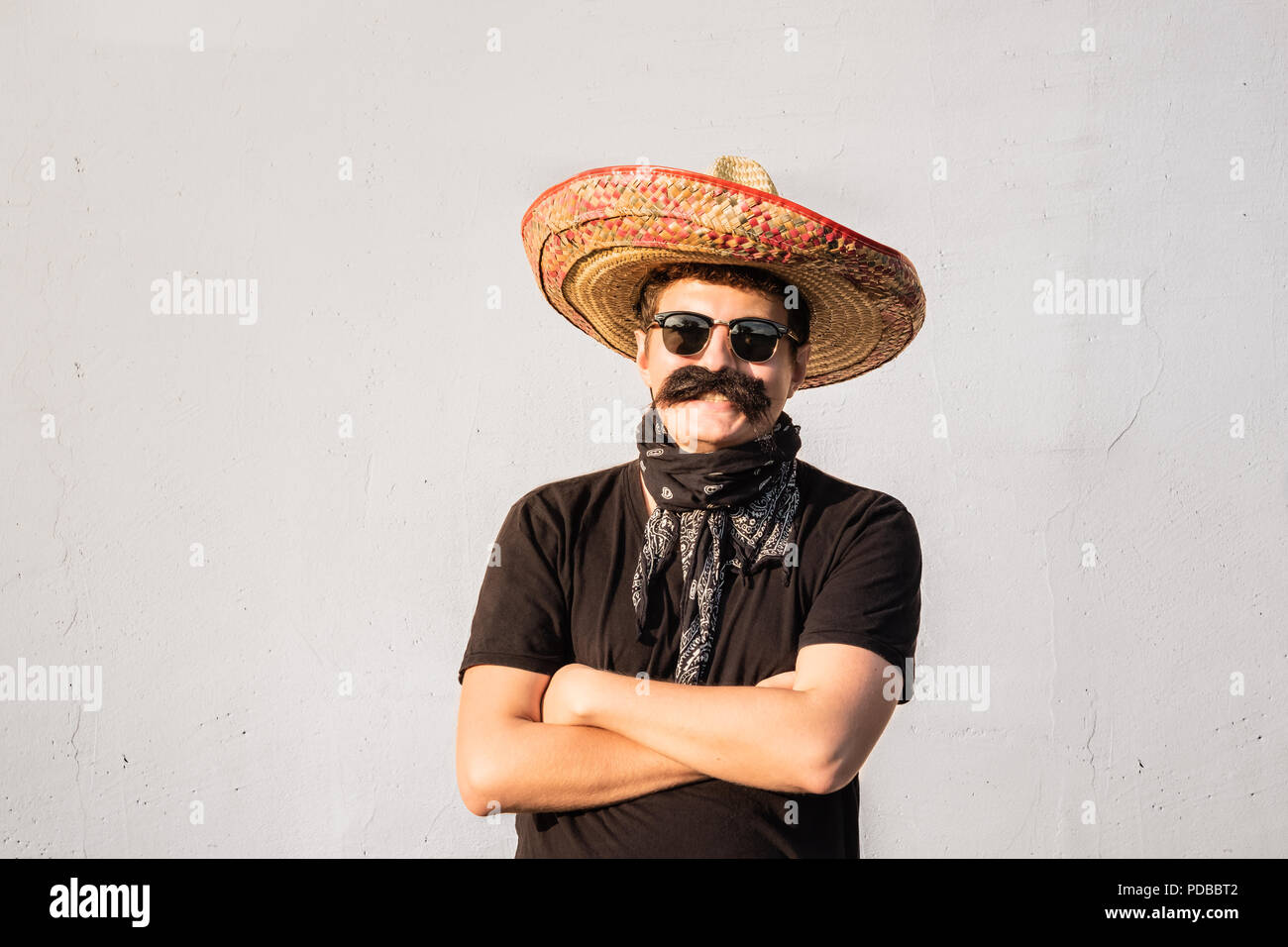 Lustige und fröhliche Mann gekleidet in traditionellen mexikanischen Sombrero, falschen Schnurrbart, bandana und Sonnenbrillen. Movember oder Halloween Konzept der Junge mal Stockfoto