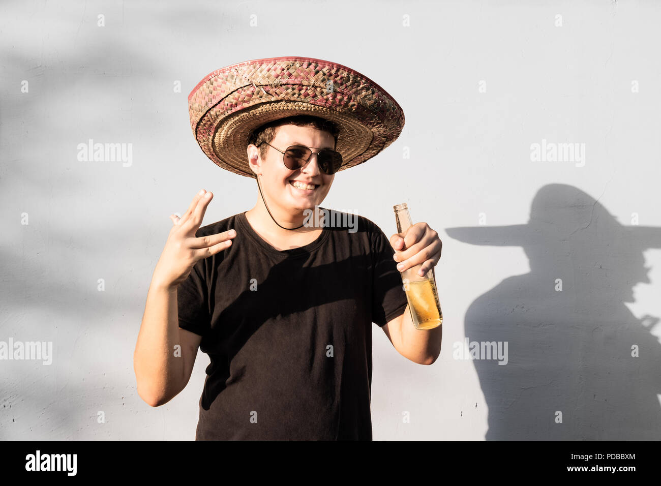 Junge männliche Person im Sombrero holding Flasche trinken. Mexiko Unabhängigkeit festliche Konzept der Mann mit nationalen Mexican Hat Party Stockfoto