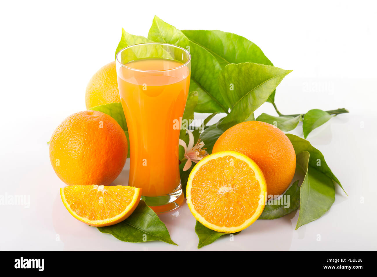 Orangen und Orange Tree Blätter neben einem Glas Orangensaft isoliert auf Weiss. Stockfoto