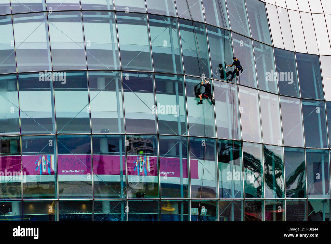 Zwei Fensterputzer arbeiten auf dem Sage, ein Wahrzeichen Konzerthalle in einem gebogenem Glas und Edelstahl Gebäude, das im Jahr 2004 eröffnete, Gateshead, Großbritannien. Stockfoto