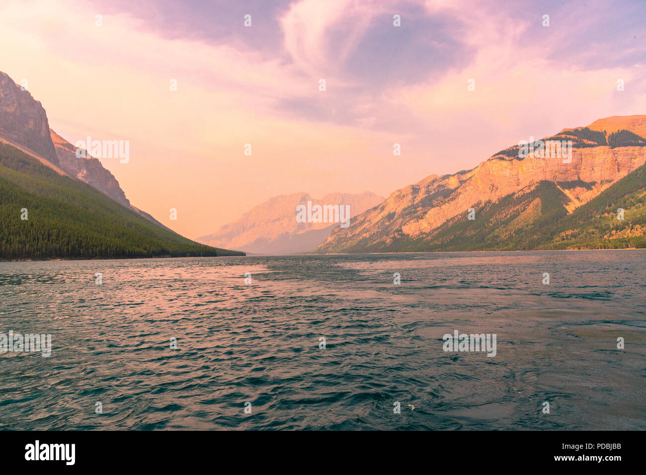 Foto Blick auf Lake Minnewanka vom Boot aus mit einem bunten Himmel und den Kanadischen Rocky Mountains im Hintergrund. Stockfoto