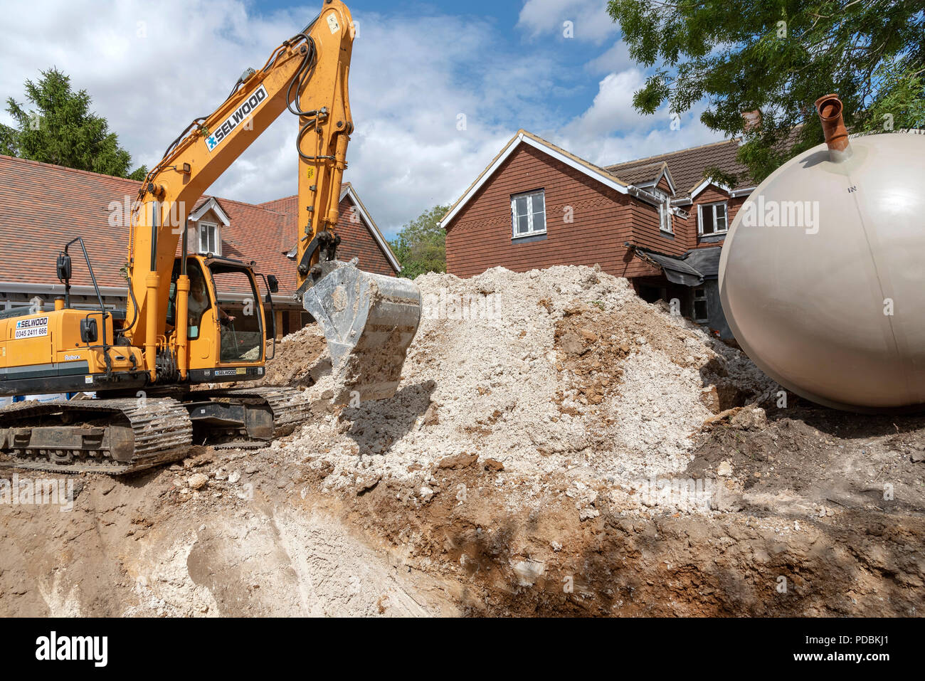 Eine Excuvator crawler Graben für einen unterirdischen Tank auf einer Wohnsiedlung in Hampshire, England, Großbritannien Stockfoto