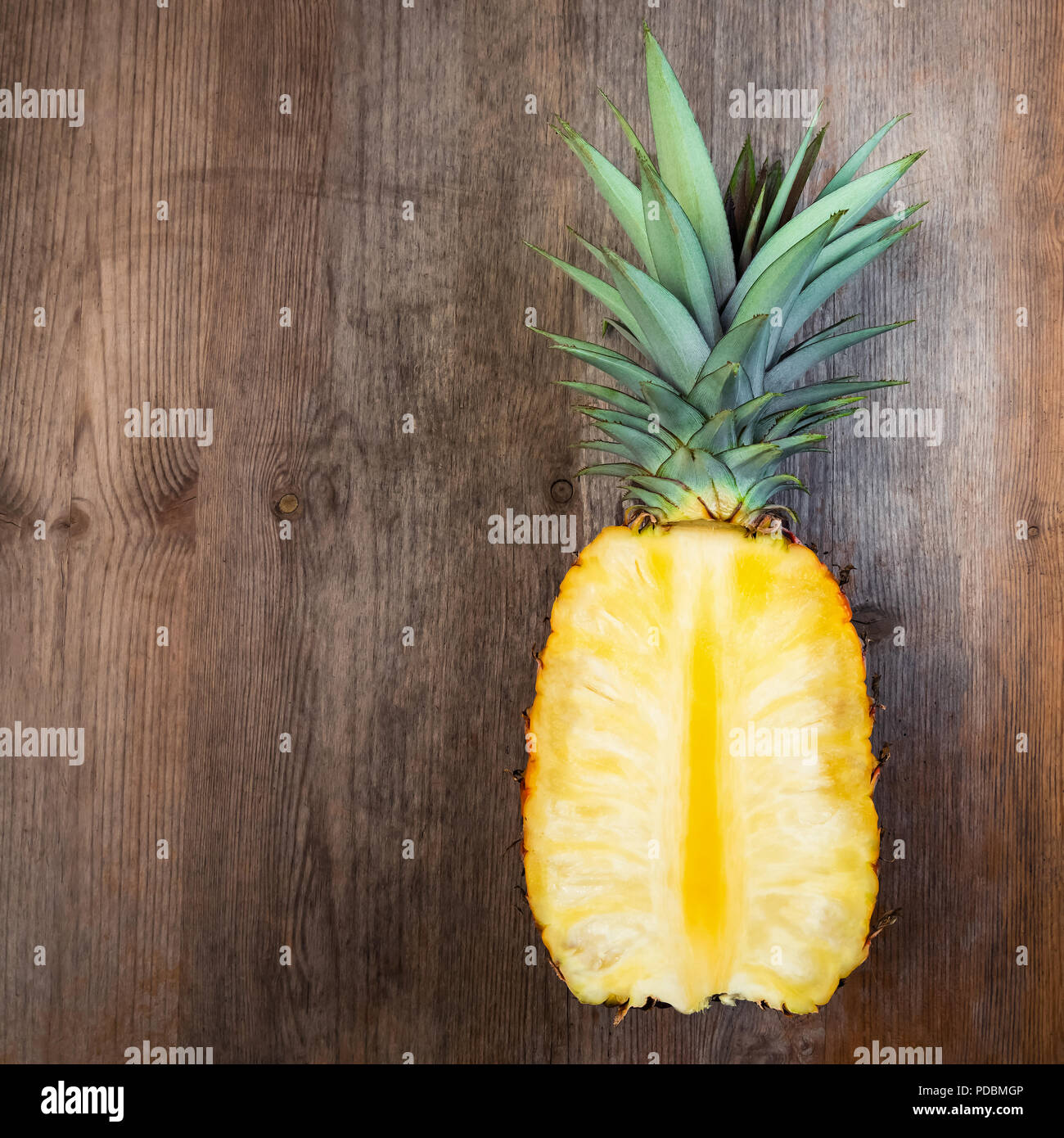 Ananas Obst schneiden die Hälfte auf Holz- Hintergrund negativer Platz. Quadratische Komposition. Juicy organisch reif und süß gewachsen Stockfoto