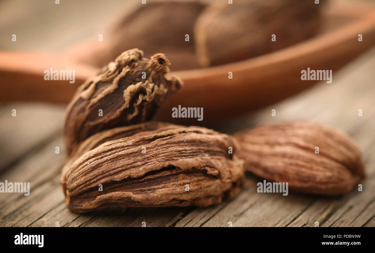 Schwarzer Kardamom mit Löffel aus Holz auf Holz Oberfläche Stockfoto