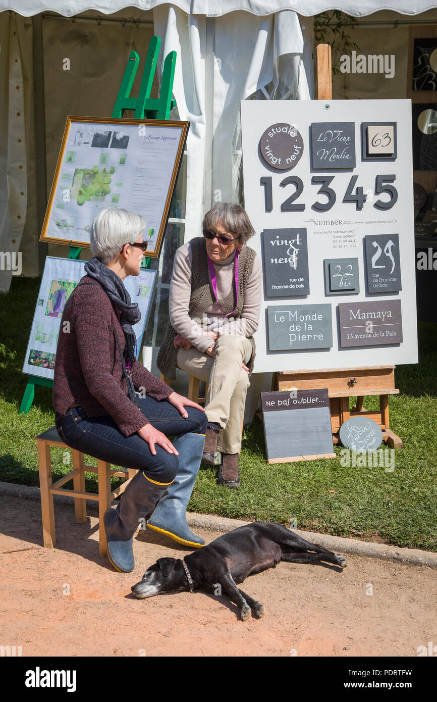 Ein paar sprechen bei der jährlichen Garten zeigen, Passionnement Jardin, in Honfleur, Normandie, Frankreich während der Hund liegt schlafend Stockfoto