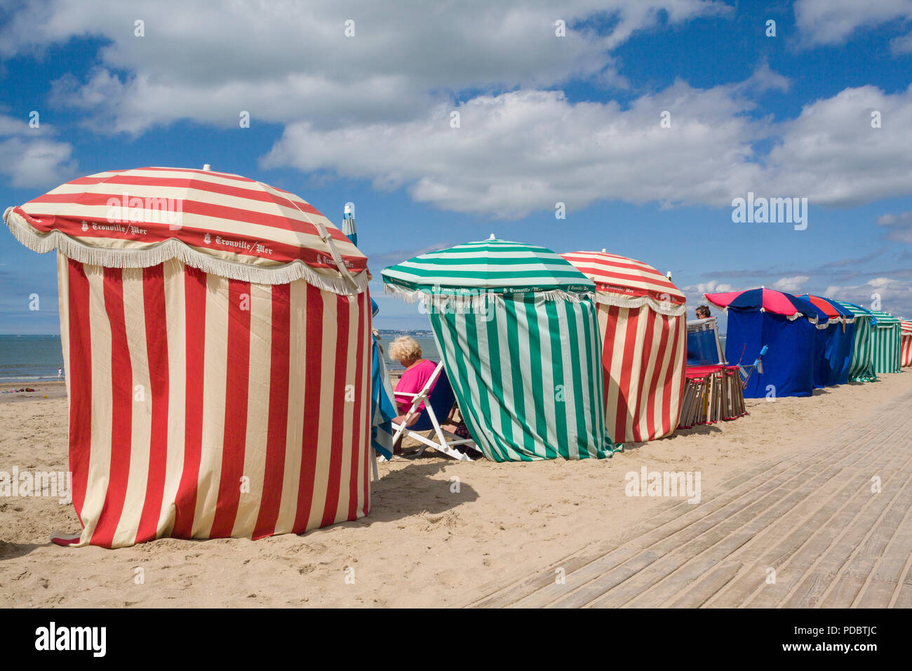 Bunt gestreiften Windschutze am Strand von Les Planches Boardwalk in Deauville, Normandie, Frankreich Stockfoto