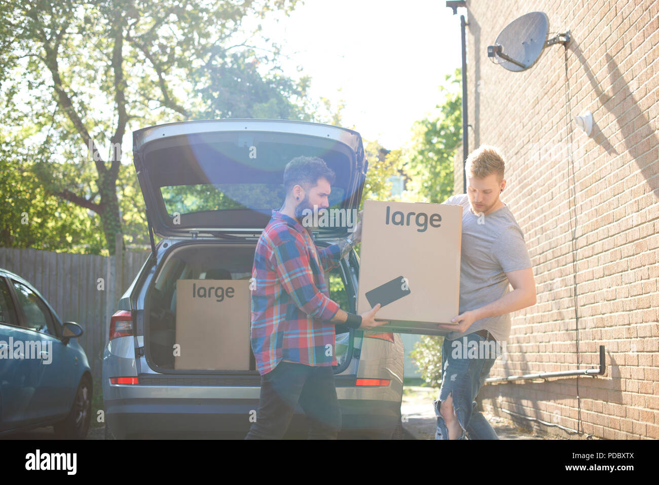 Männliche homosexuelle Paare entladen Kisten aus dem Auto Stockfoto