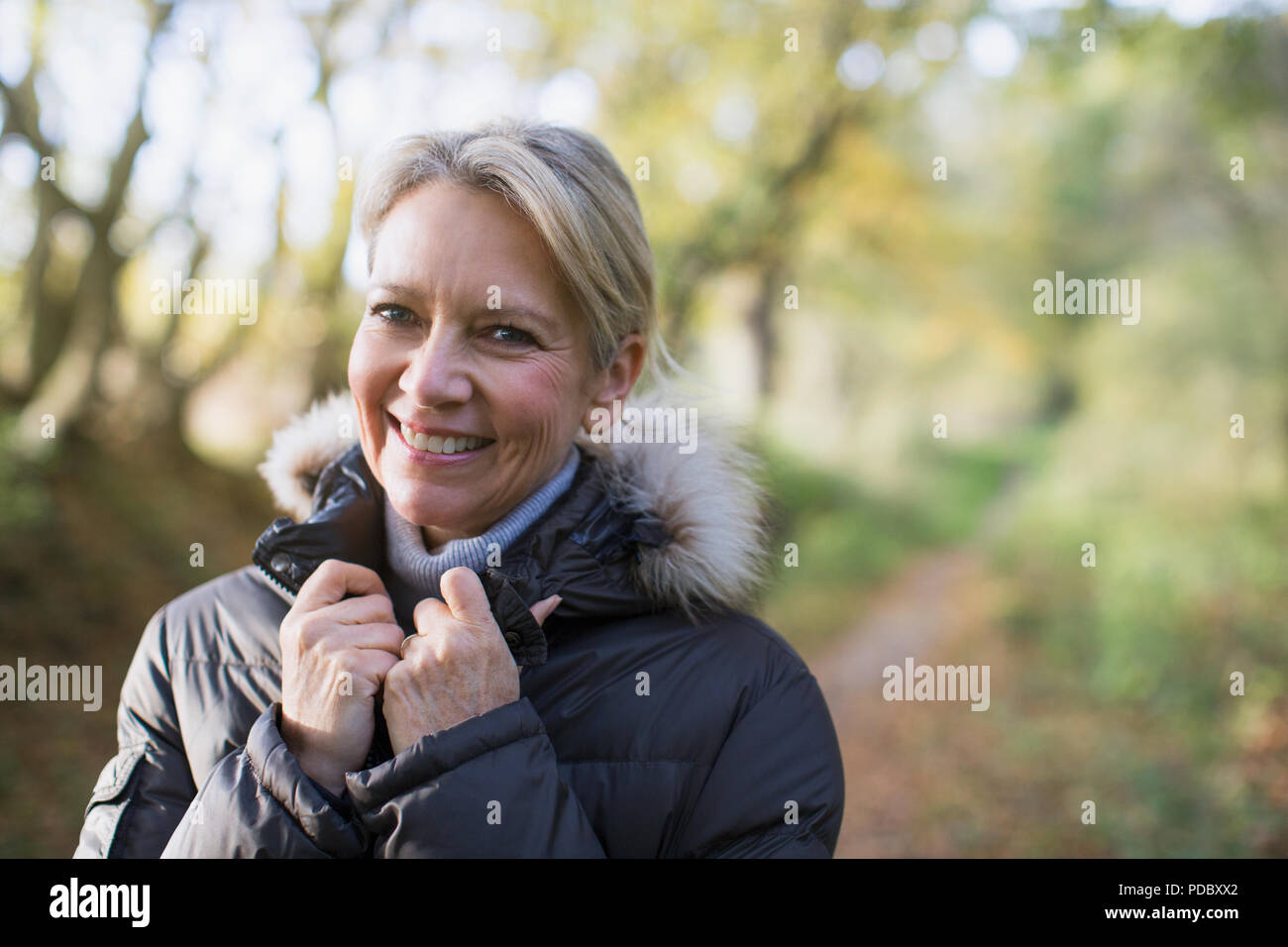 Porträt Lächeln, zuversichtlich, reife Frau in Parka in Wäldern Stockfoto