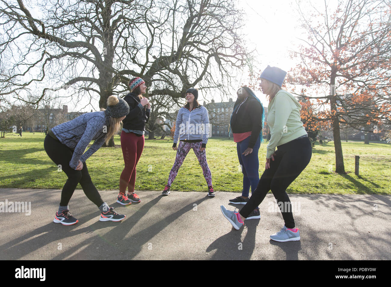 Läuferinnen Stretching und Sprechen im sonnigen Park Stockfoto