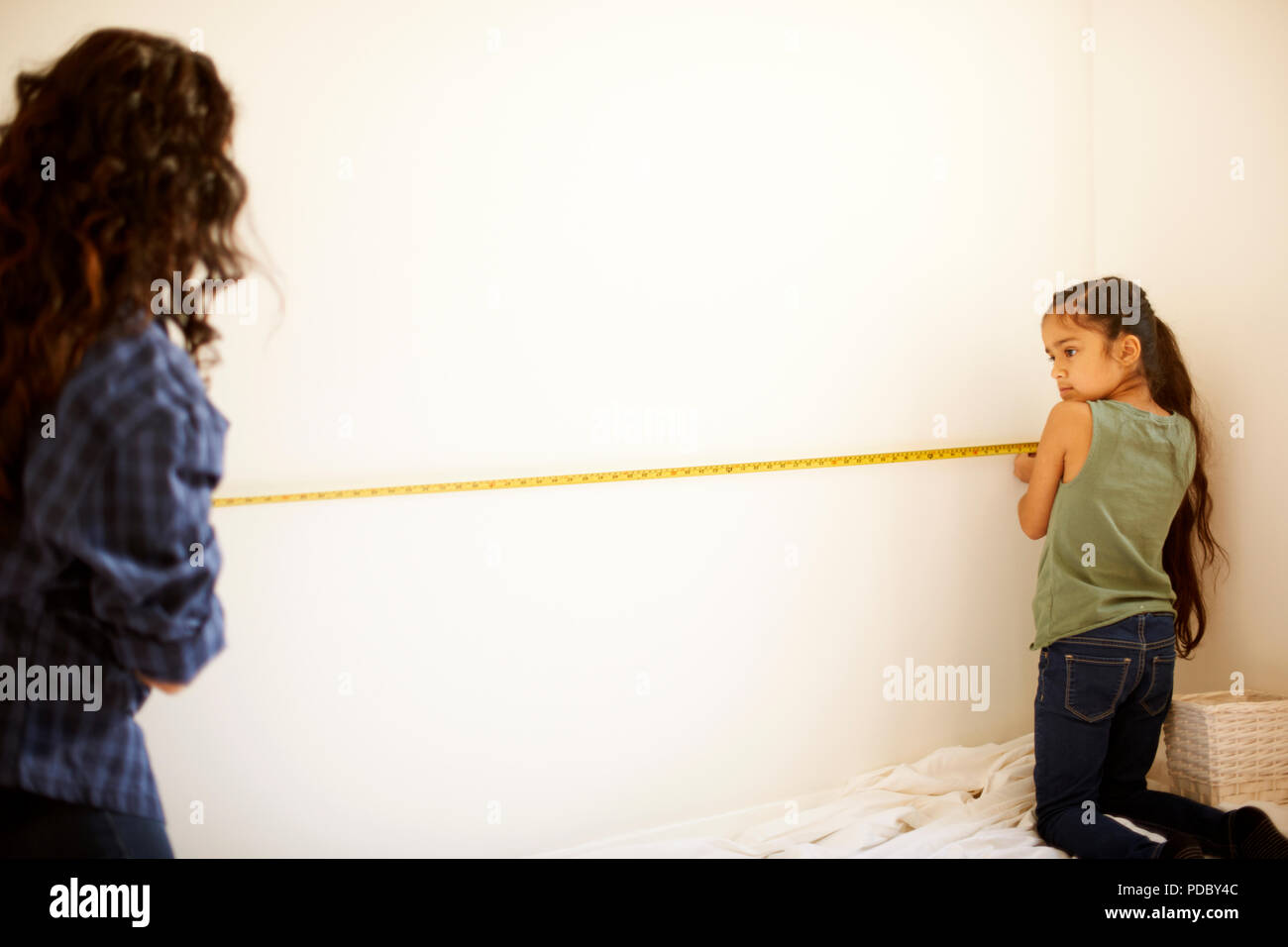 Mutter und Tochter messen Wand für Projekt Stockfoto