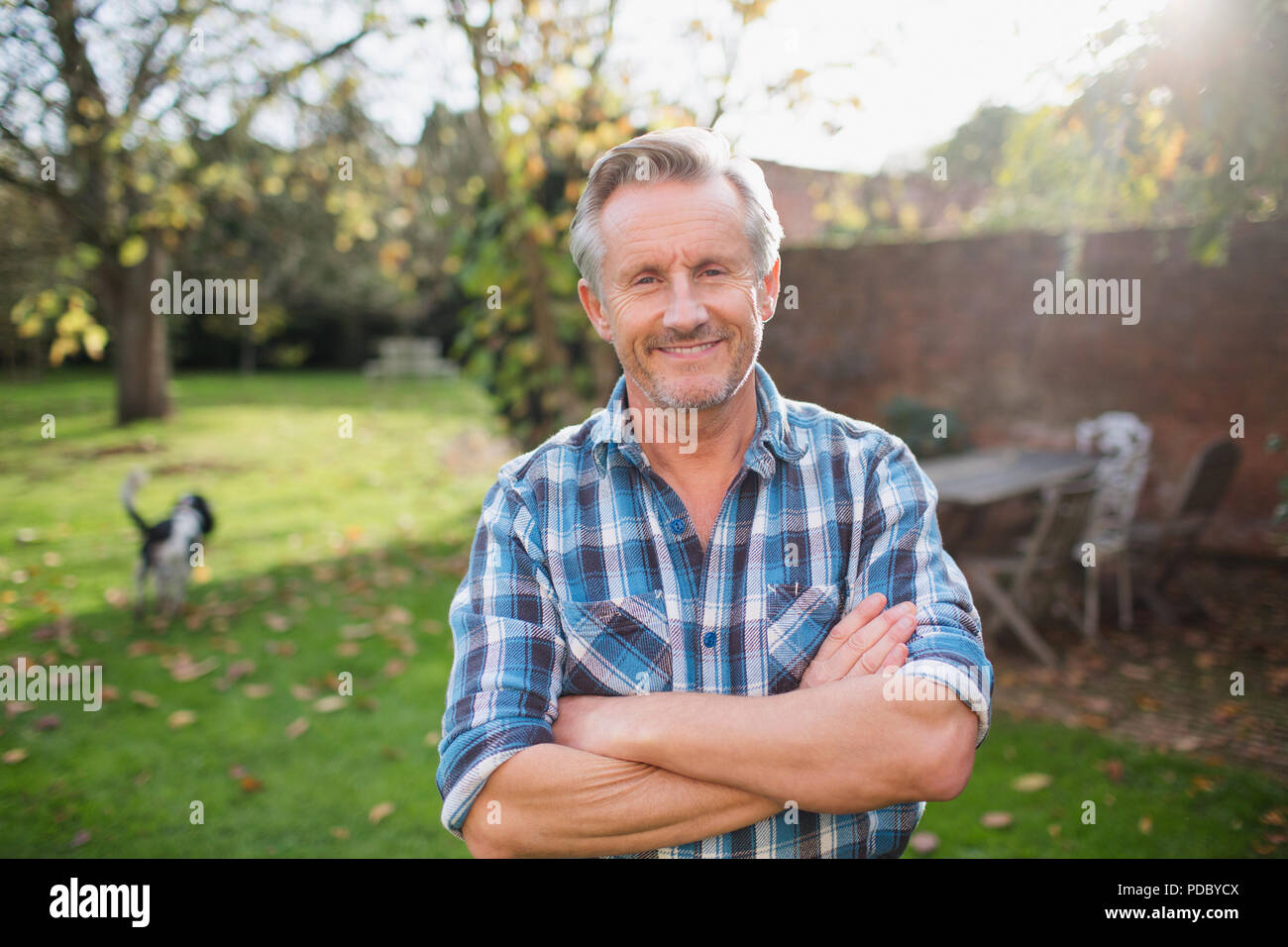 Portrait zuversichtlich älterer Mann im sonnigen Herbst Hinterhof Stockfoto