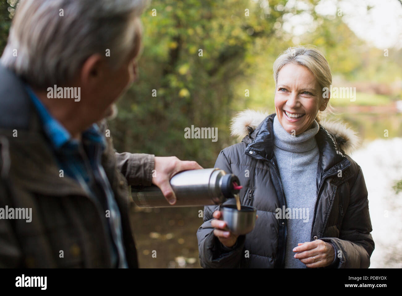 Gerne reifes Paar trinken Kaffee trinken von isolierten Behälter im Herbst Park Stockfoto