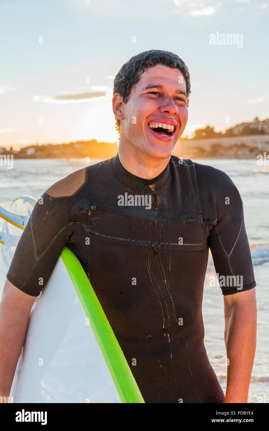 Lachende männliche Surfer mit Surfbrett am Strand. Stockfoto