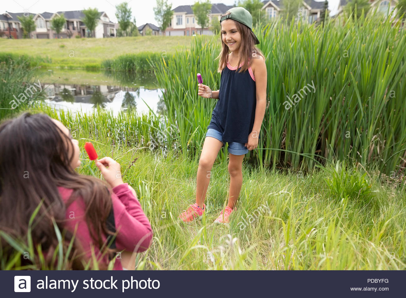 Girl Friends Essen gewürzt Eis im hohen Gras Stockfoto