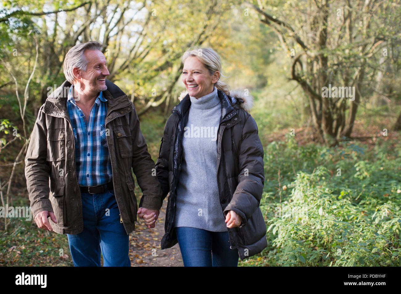 Glücklich, zärtlich Reifes Paar halten sich an den Händen und gehen im Herbst Park Stockfoto