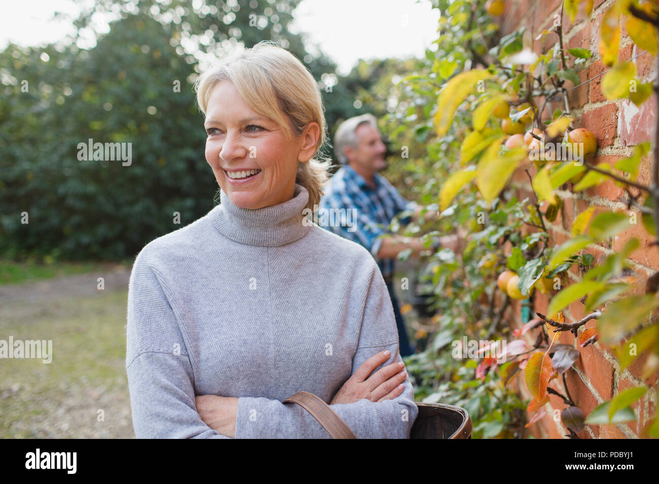 Portrait glücklich, selbstbewusst, reife Frau ernten Äpfel im Garten Stockfoto
