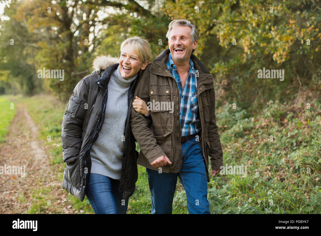 Glückliche, unbeschwerte Reifes Paar gehen Arm in Arm im Herbst Park Stockfoto