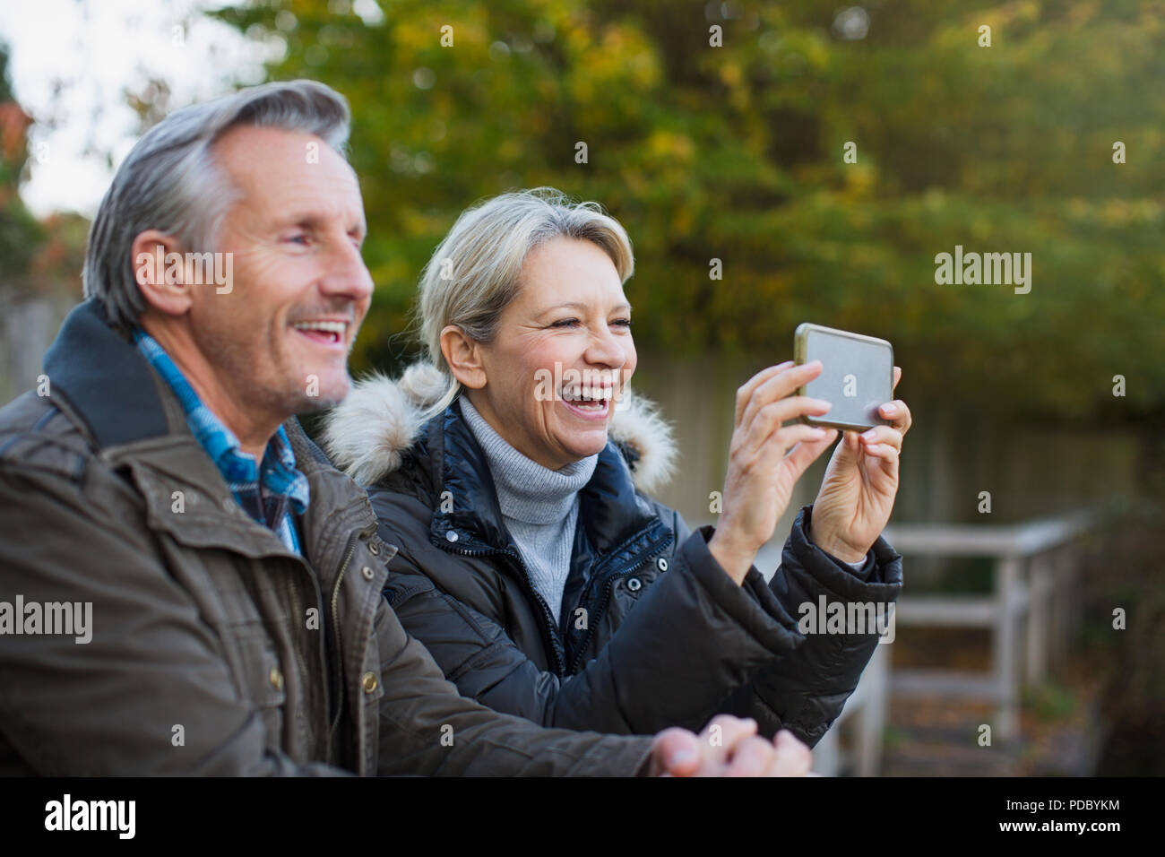 Glückliches junges Paar mit Kamera Handy in Park Stockfoto