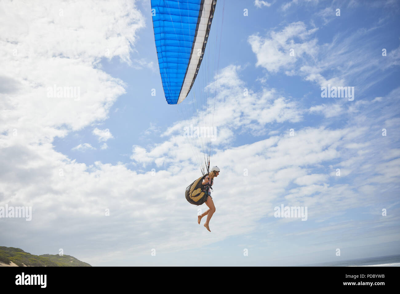 Weibliche Gleitschirm paragliding gegen sonnigen blauen Himmel Stockfoto