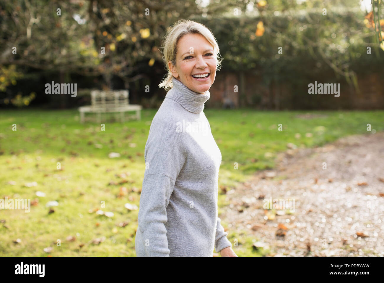 Porträt Lächeln, zuversichtlich, reife Frau im sonnigen Herbst Hinterhof Stockfoto