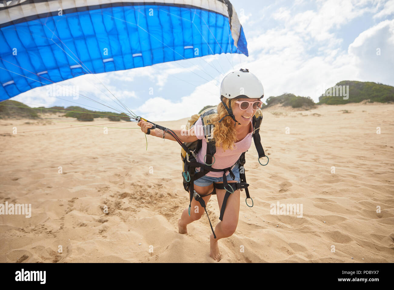 Lächelnd weibliche Gleitschirm mit Fallschirm am Strand Stockfoto