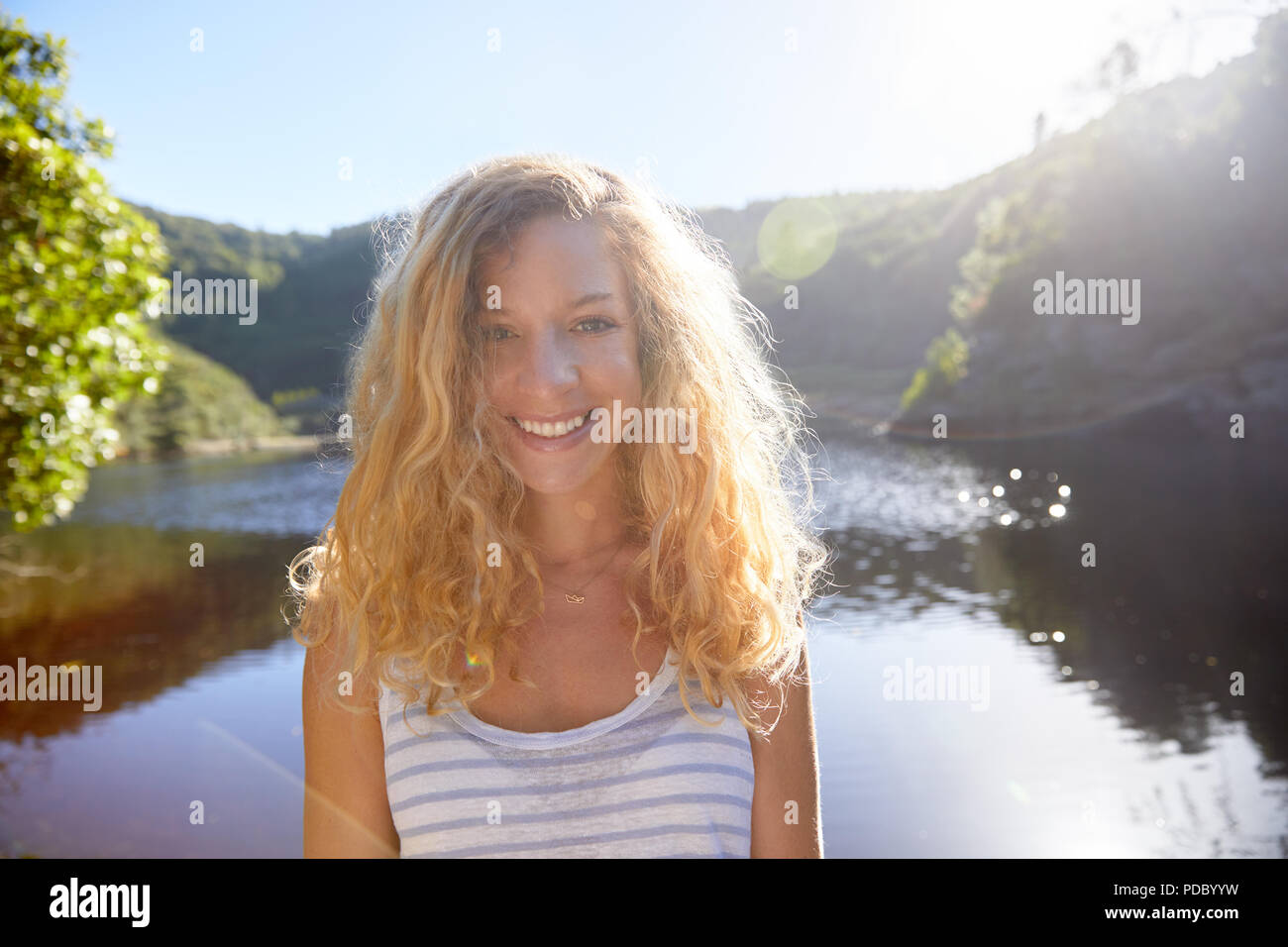 Porträt Lächeln, selbstbewussten jungen Frau an sonnigen Sommer See Stockfoto