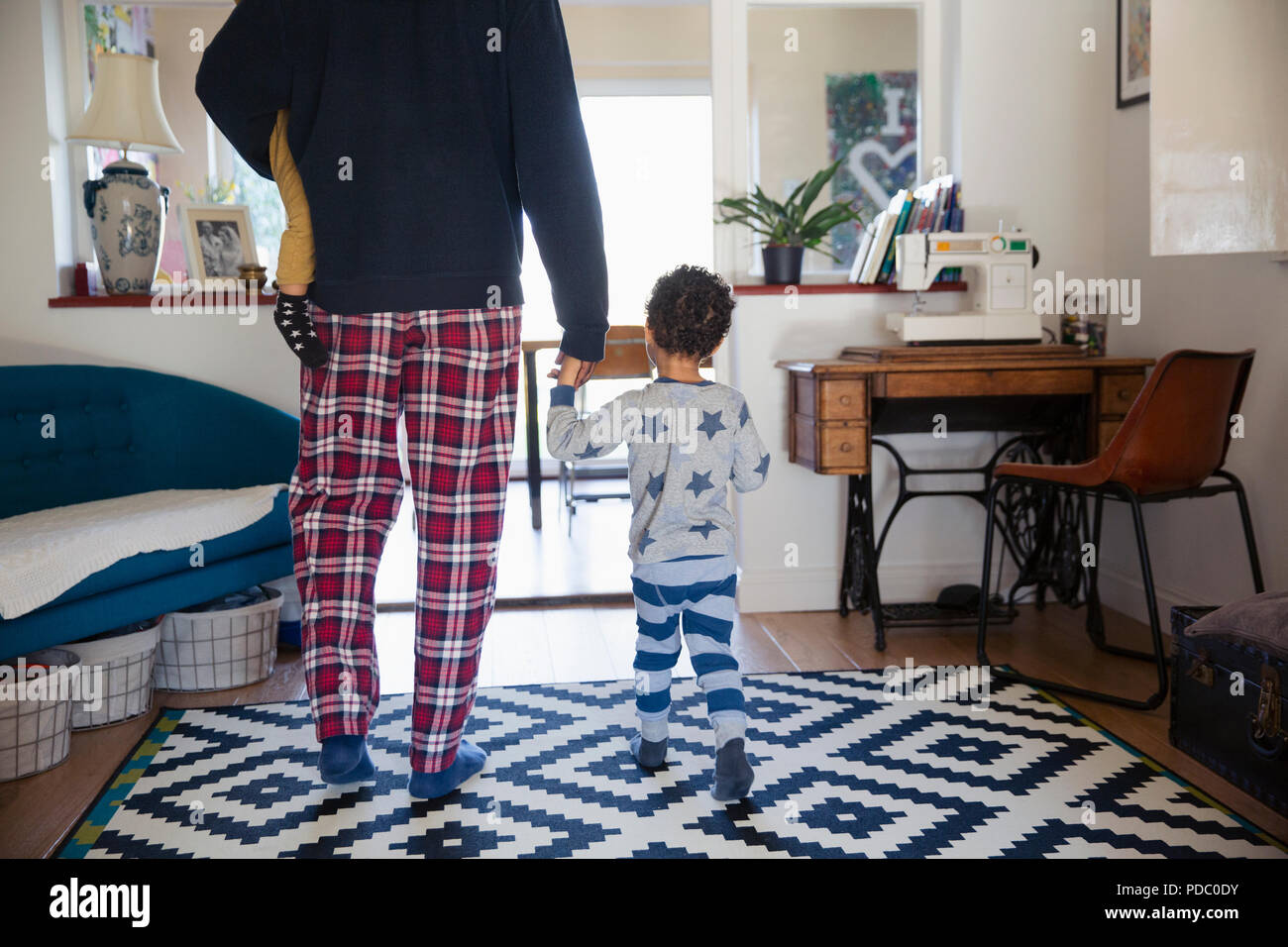 Vater und Söhne im Schlafanzug zu Fuß im Wohnzimmer Stockfoto