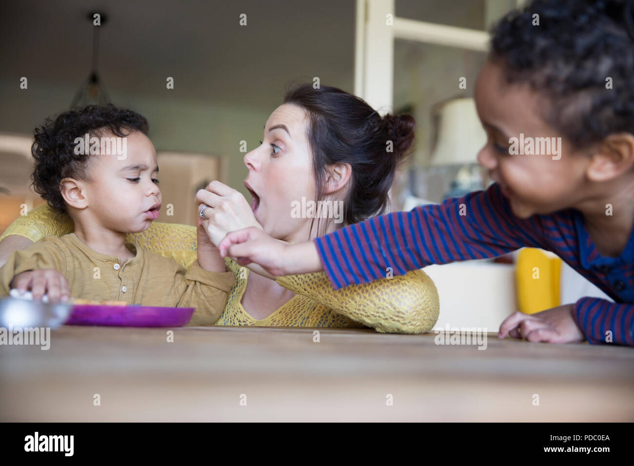Verspielte Mutter feeding baby Sohn am Tisch Stockfoto