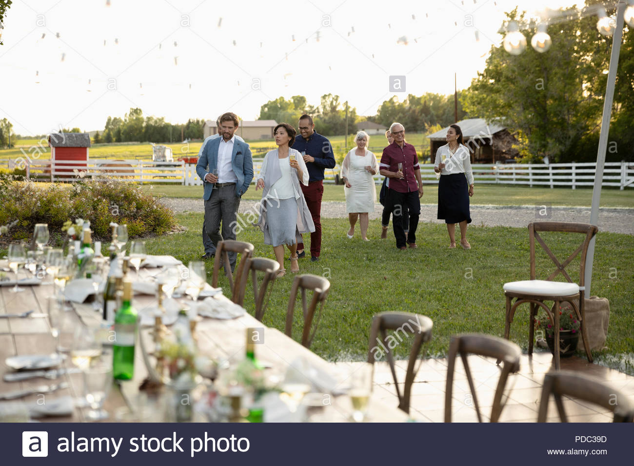 Freunde zu Fuß in Richtung Hochzeit Tabellen in ländlichen Garten Stockfoto
