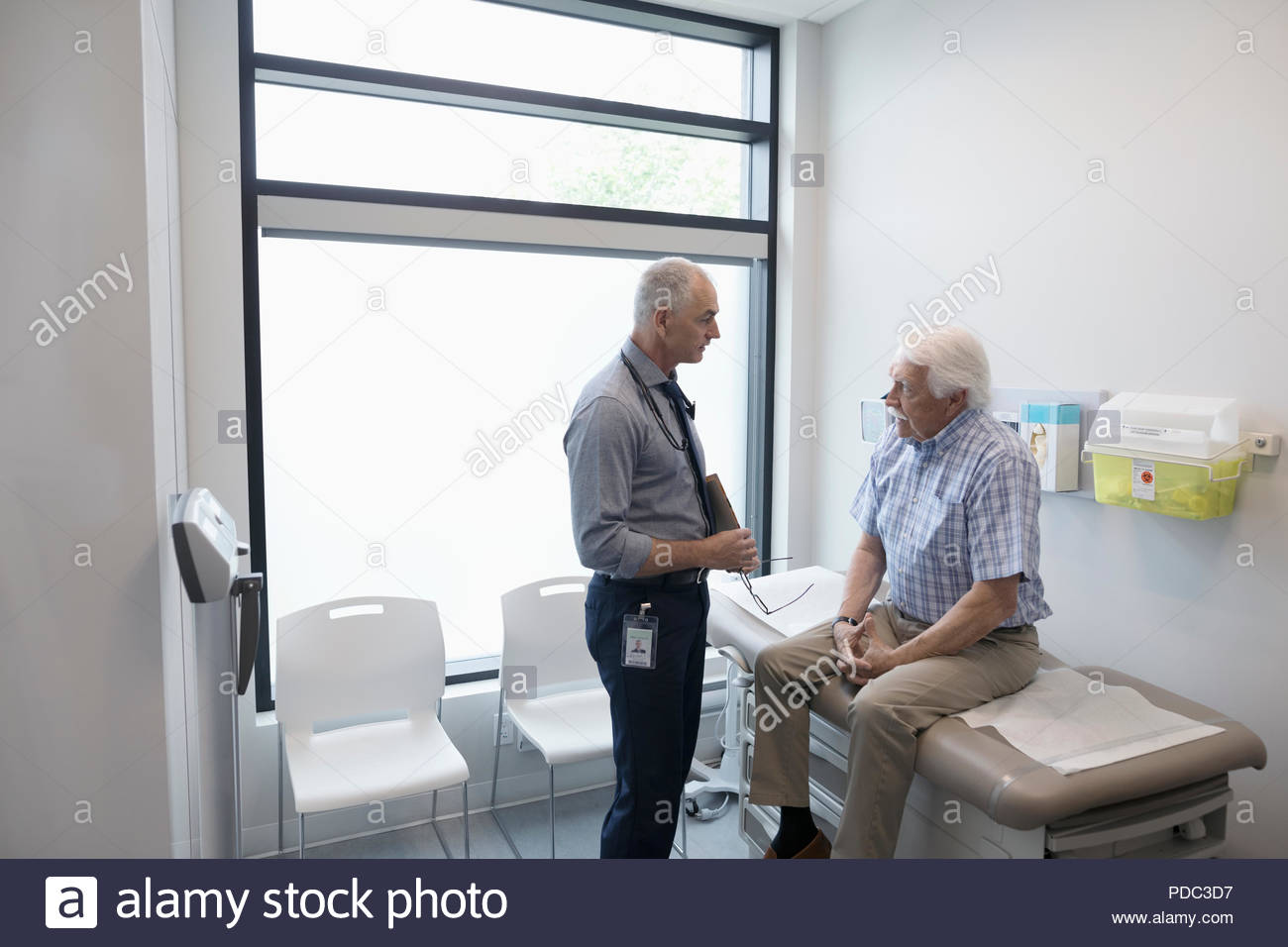 Männlicher Arzt im Gespräch mit älteren Patienten in Klinik Untersuchungsraum Stockfoto