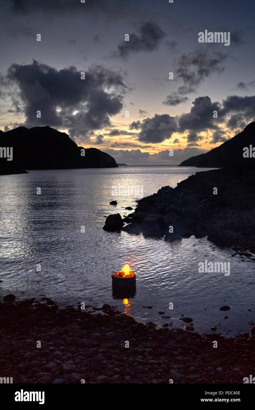 Durch firestack Künstlerin Julie Bach. an der Westküste der Insel Lewis. Schottland. Elemental Skulptur der Hohle Stein Cairn mit Feuer leuchtet auf einer Flut Stockfoto