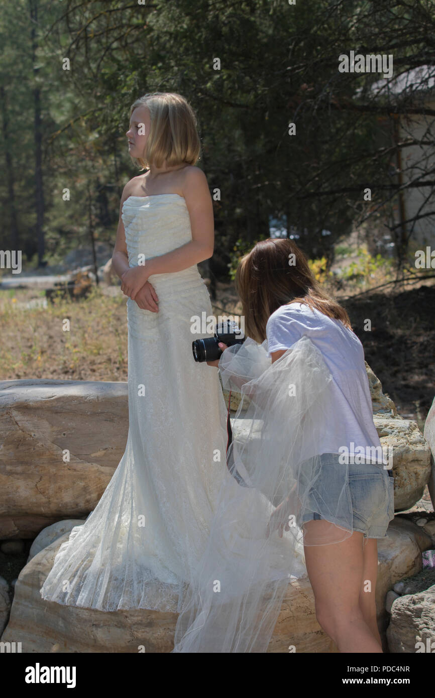 Junge Frau mit einem Hochzeitskleid der Tante Kleid, wie Tante ordnet das Kleid für ein Foto geschossen, auf den Felsen. Vertikale und sowohl Modell freigegeben. Stockfoto