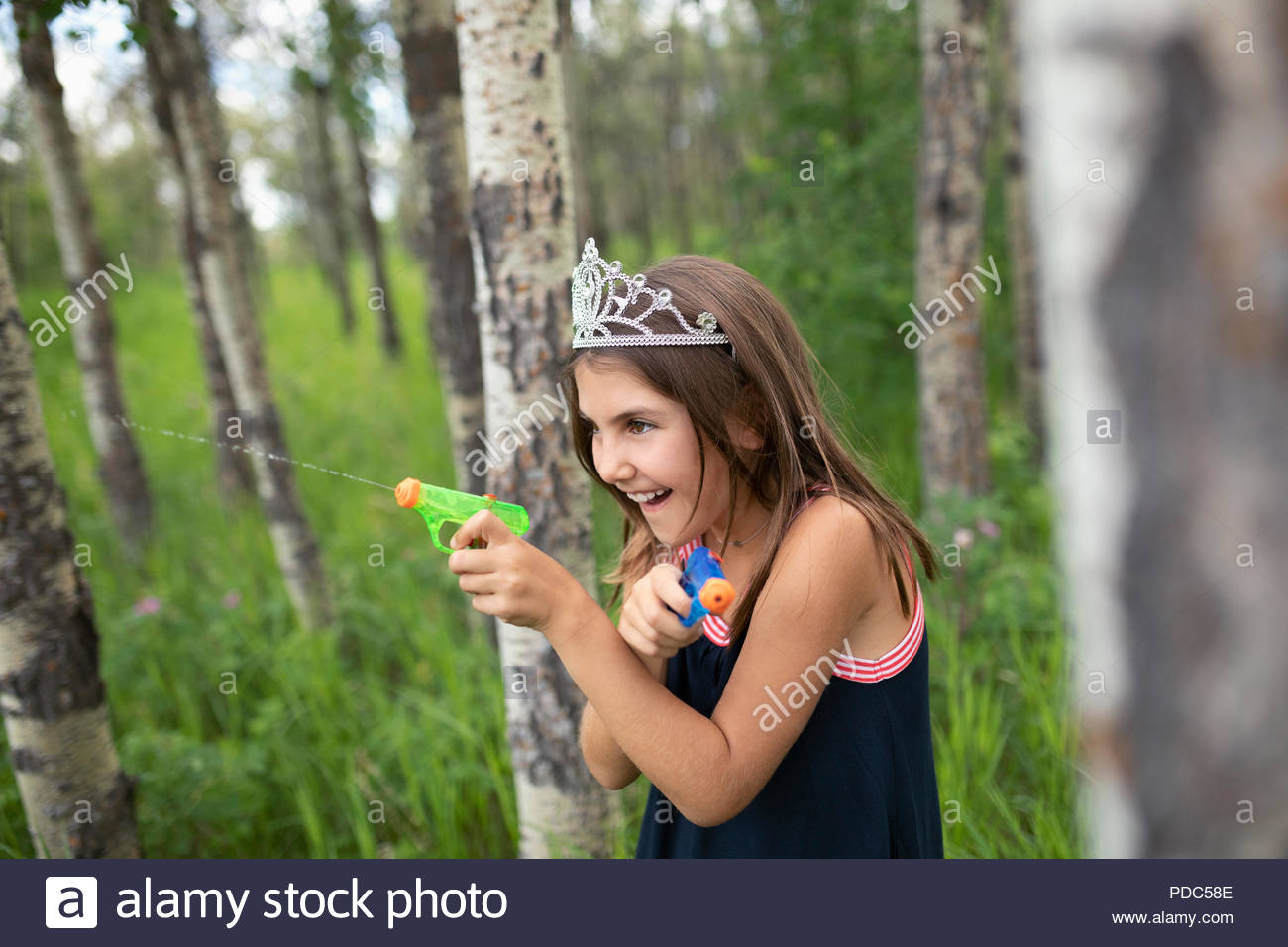 Verspielte Mädchen Tiara mit sprizen Gewehren in Wäldern Stockfoto