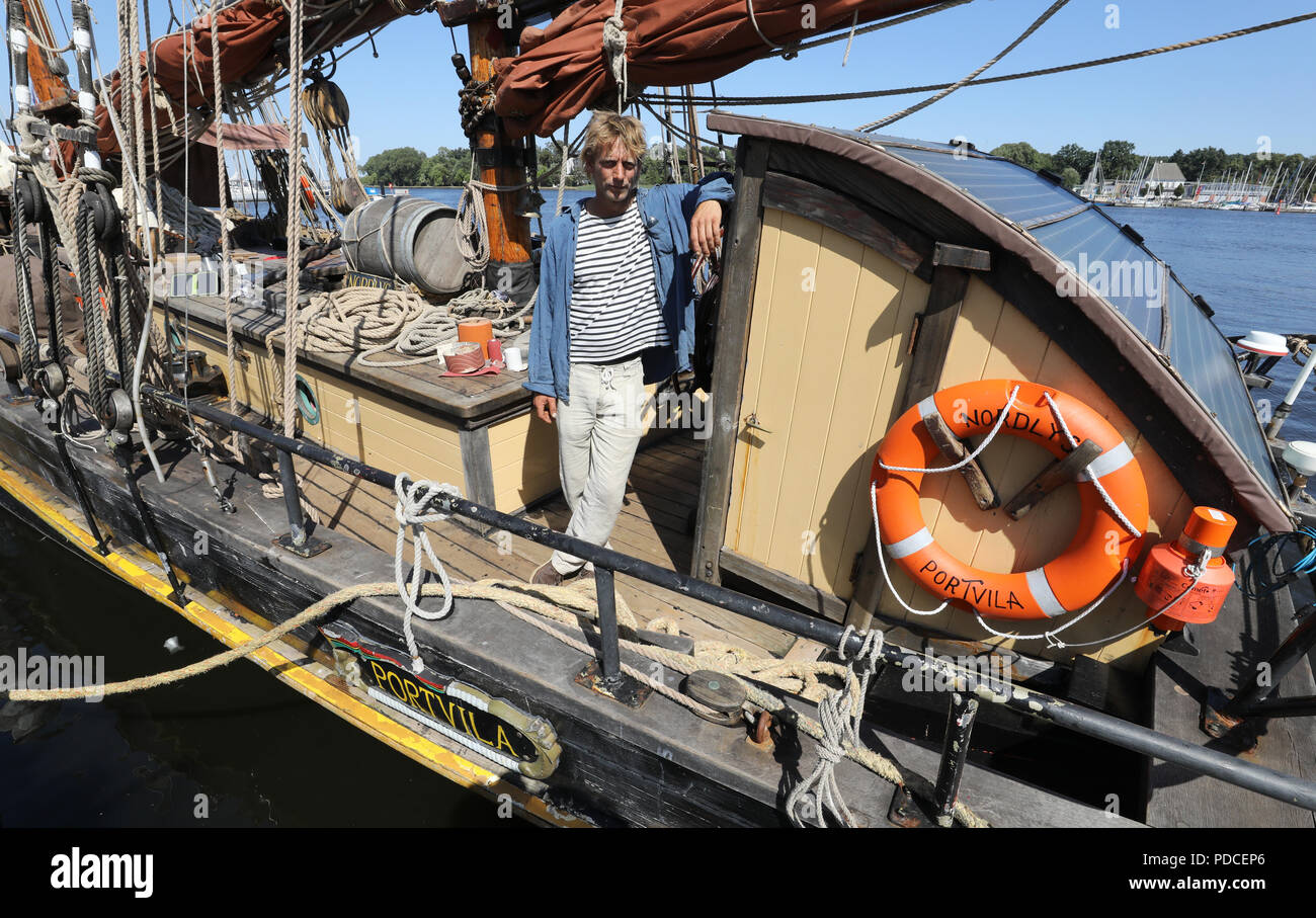 Rostock, Deutschland. 07 Aug, 2018. Kapitän Lammert Osinga steht an Bord seiner "Nordlys" (Norwegisch für Northern Lights). Die wohl ältesten Handelsschiff der Welt ist eine exotische unter den Gästen der Hanse Sail, die am 09. August 2018 eröffnet wird: 1873 erbaut, das Schiff hat keine Hilfsmotor und kann deshalb nicht nehmen Sie Teil an den Kreuzfahrten. In diesem Jahr, es war ziemlich rot Wein an Bord produziert. Der cutter Segeln unter der Flagge Vanuatu ist, die im Auftrag von Fairtrade. Quelle: Bernd Wüstneck/dpa/Alamy leben Nachrichten Stockfoto