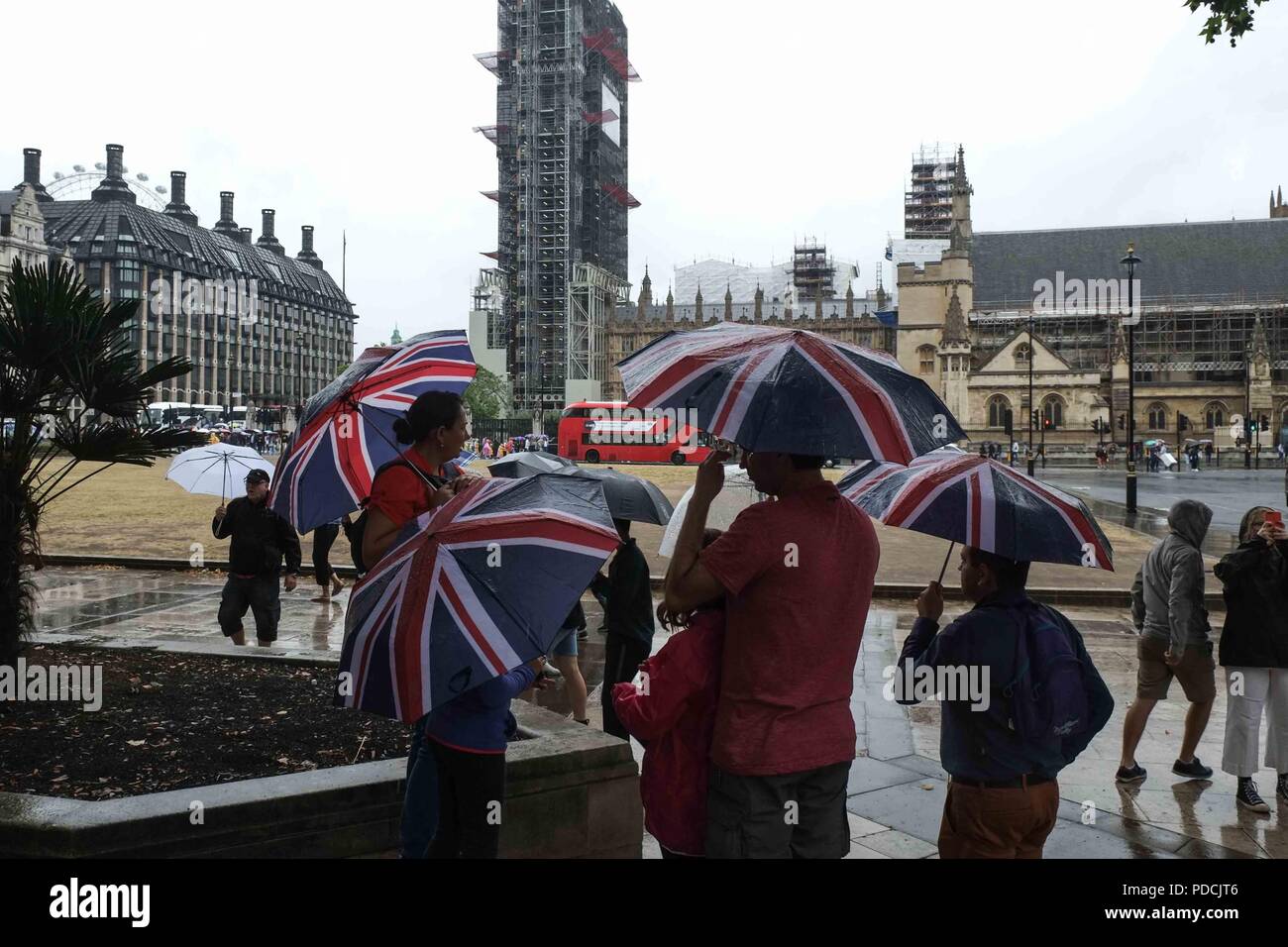 London, 9. August 2018: Touristen in Parliament Square Schutz vor dem Regen unter Regenschirmen. Credit: Claire Doherty/Alamy leben Nachrichten Stockfoto