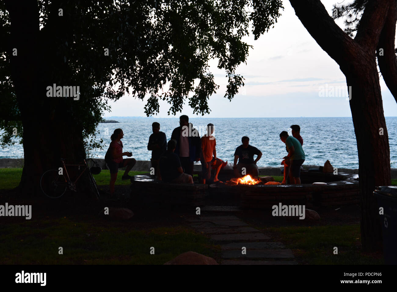 Studenten von der Universität von Chicago sind gegen Michigan See in den Abend Silhouette, wie Sie um eine Feuerstelle auf Vorgebirge Punkt sammeln. Stockfoto