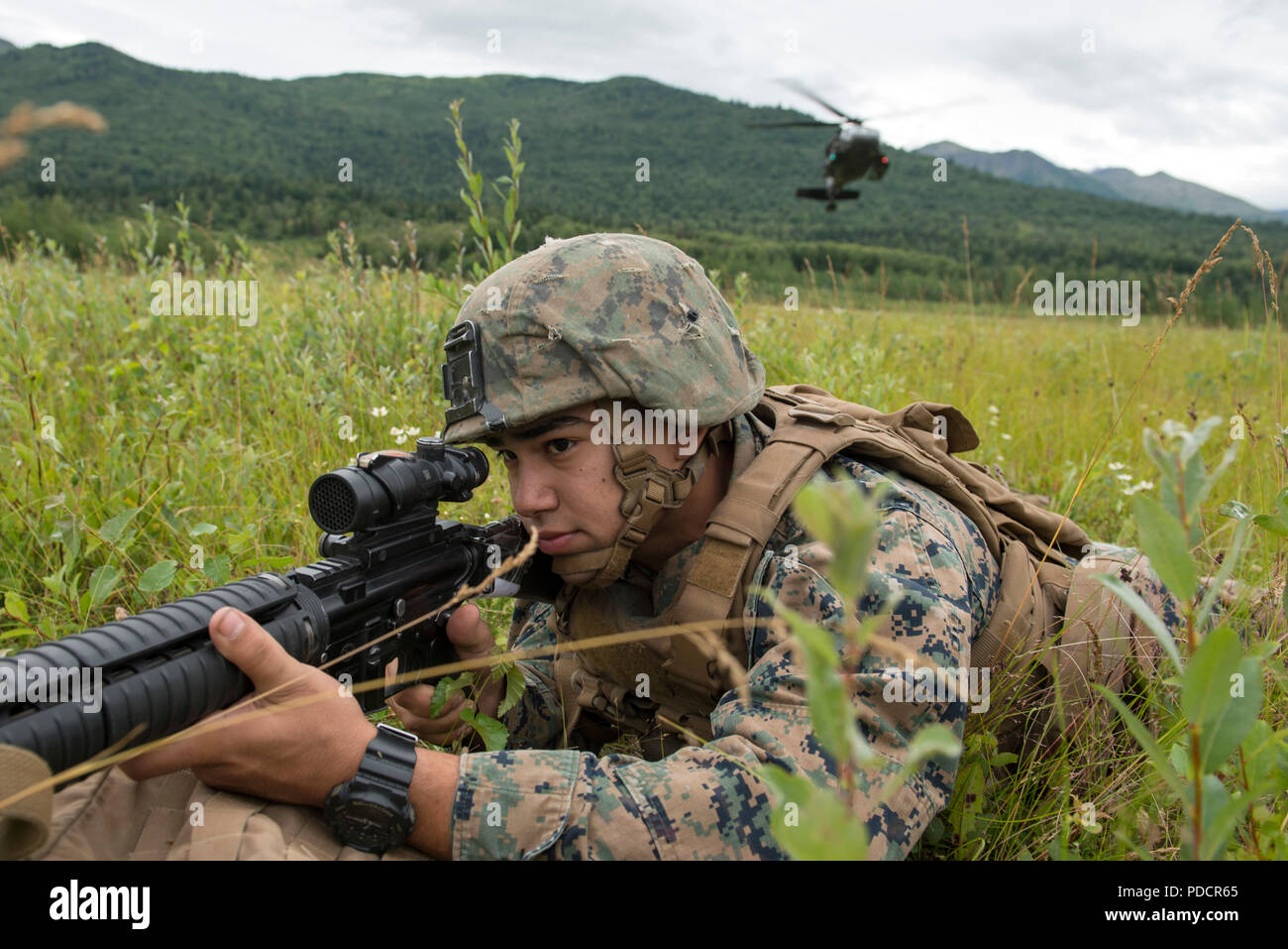 Us Marine Corps Lance Cpl. Ismael Garcia II., Charlie Company, 1.Bataillon, 23 Marine Regiment zugeordnet, hält Sicherheit als Alaska Army National Guard UH-60 Black Hawk Hubschrauber, mit dem 1. Bataillon, 207 Aviation Regiment, Ansätze der Landing Zone im 4. Marine Division Super Squad Wettbewerb im Joint Base Elmendorf-Richardson, Alaska, Aug 6, 2018 statt. Während der mehrtägigen Wettbewerb, Gruppen von 1. und 3 Bataillonen, 23 Marine Regiment und 1 Bataillon, 24 Marine Regiment, übte ihre technischen und taktischen Fertigkeiten von in Veranstaltungen, Hi konkurrierenden Stockfoto