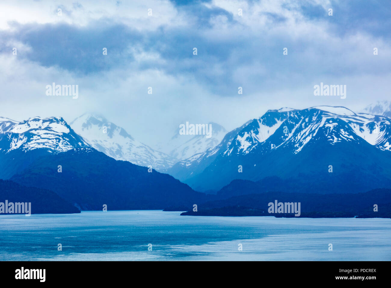 Die schneebedeckten schroffen felsigen Berge in Wolken über die Kachemak Bucht von zu Hause aus auf die Alaska Kenai Halbinsel in Homer, Alaska Stockfoto