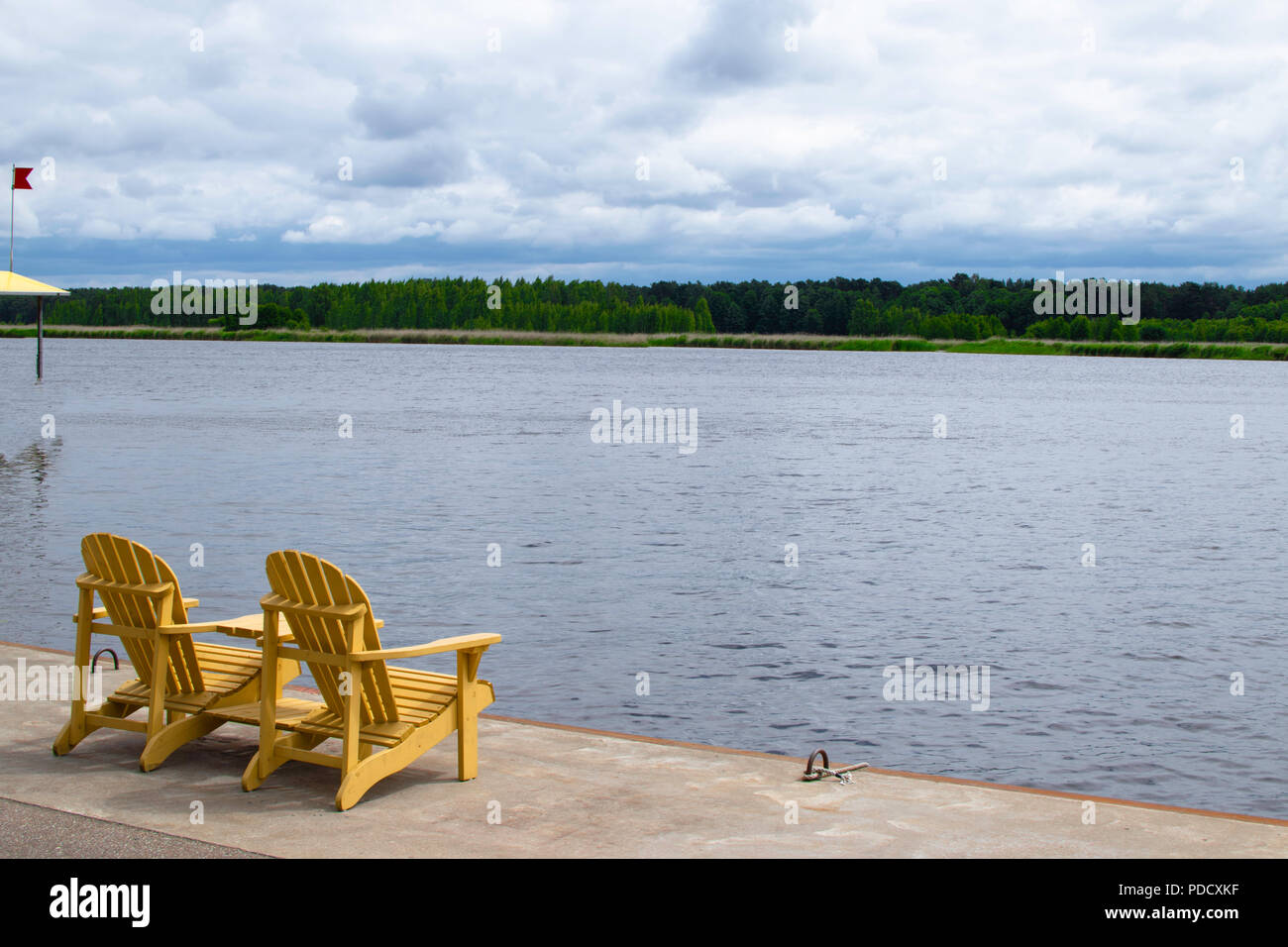 Zwei Muskoka Stühle auf einer Holzterrasse mit Blick auf einen ruhigen See Stockfoto