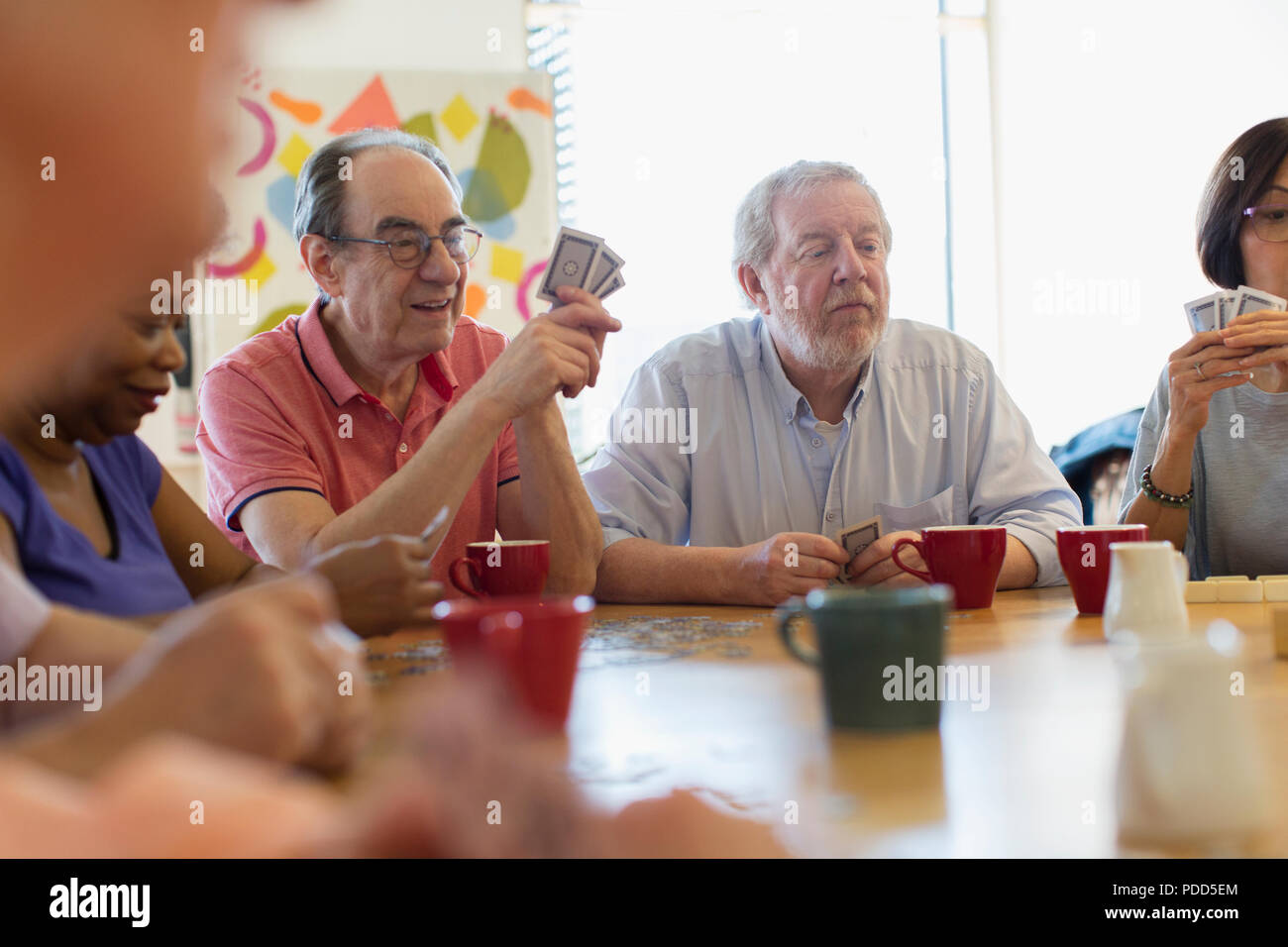 Senior Freunden Karten spielen und trinken Kaffee im Community Center Stockfoto