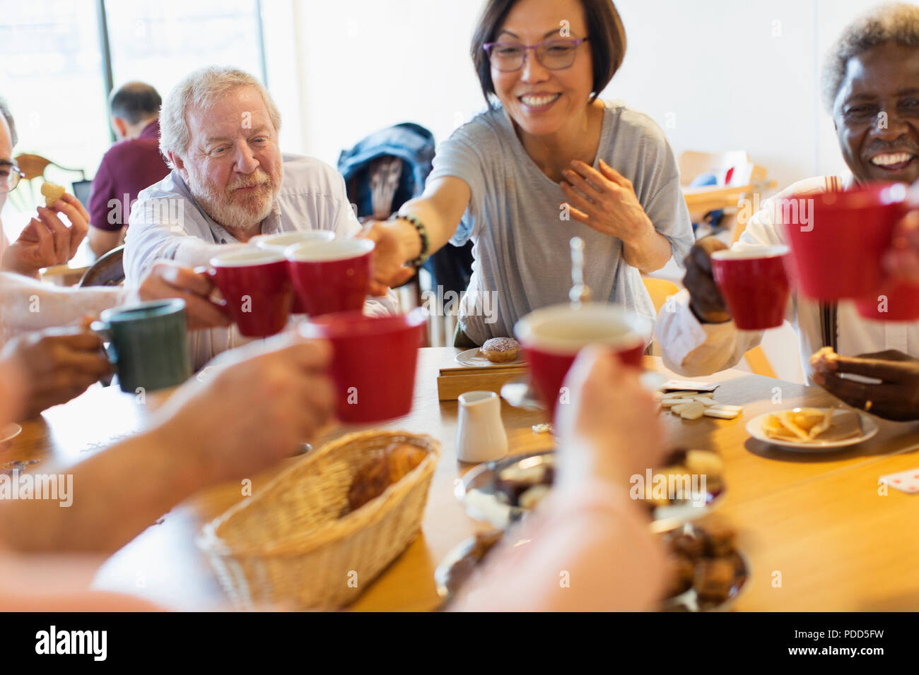 Gerne ältere Freunde genießen Nachmittagstee, toasten Becher in Community Center Stockfoto