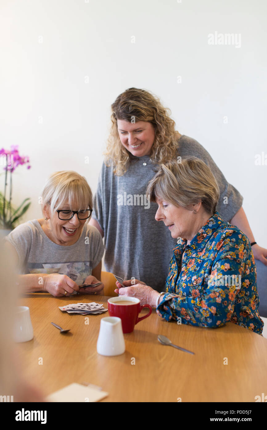 Freiwillige beobachten, ältere Frauen, die Karten am Tisch in der Mitte Stockfoto