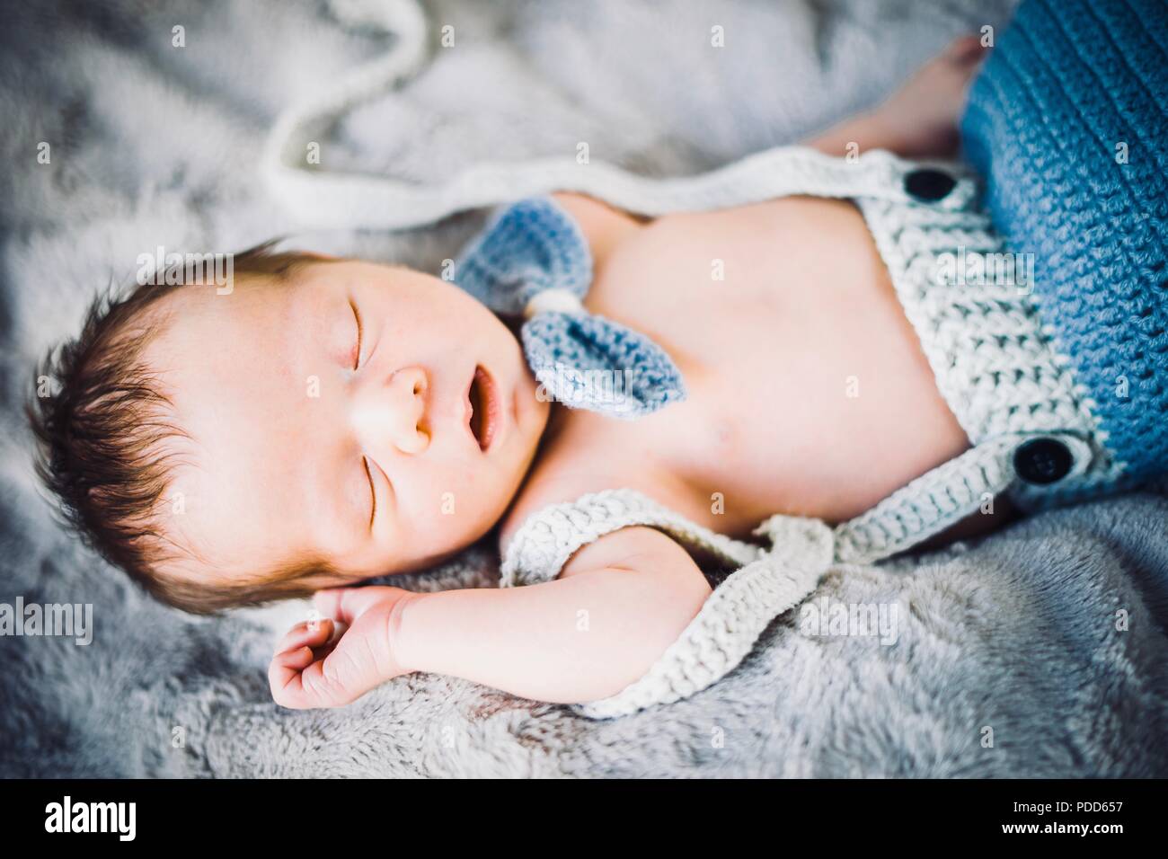 Ein neugeborenes Baby schlafen in Blau und Grau Fliege und Hosen aus Gewirken Stockfoto