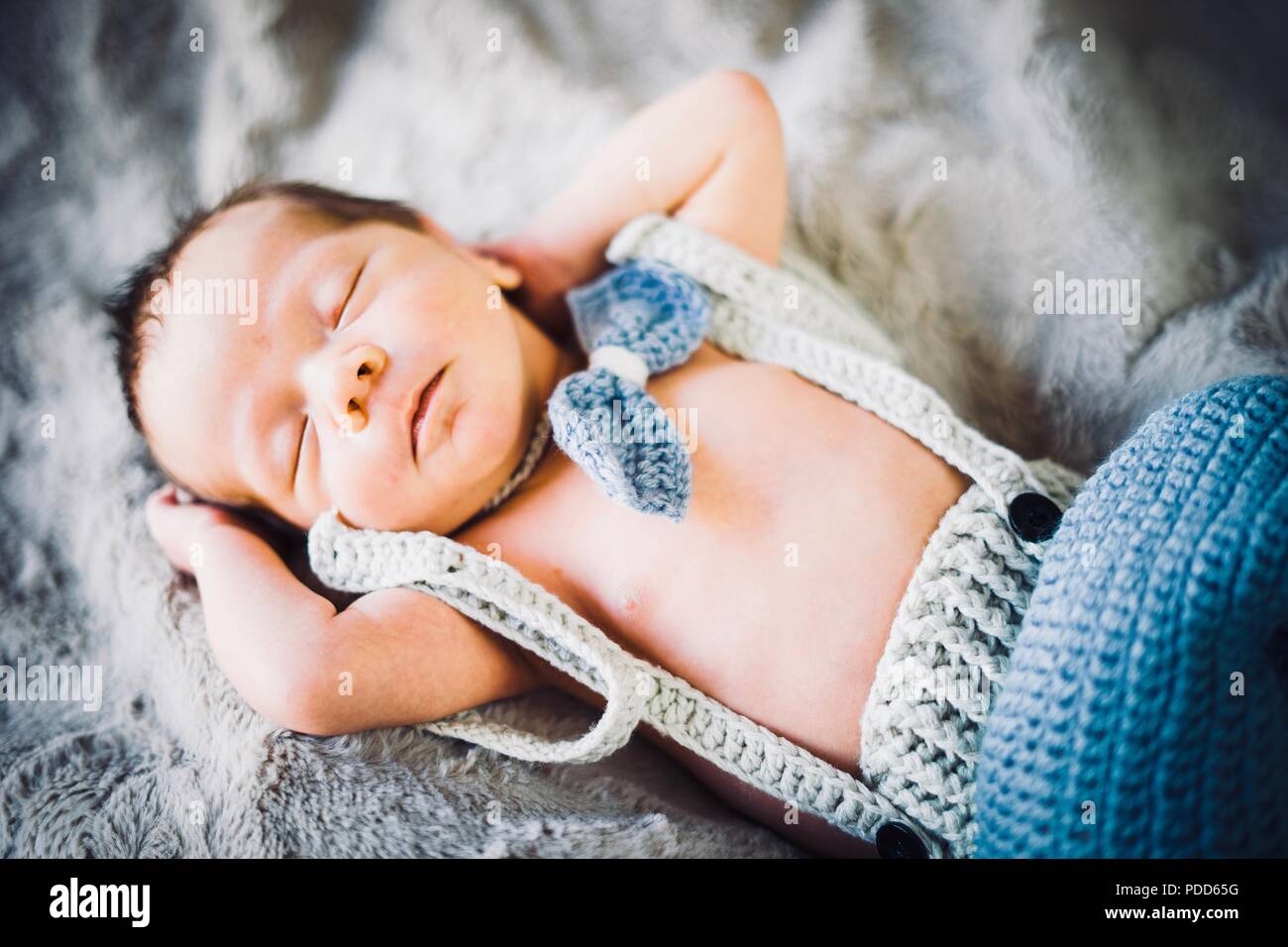 Ein neugeborenes Baby schlafen in Blau und Grau Fliege und Hosen aus Gewirken Stockfoto