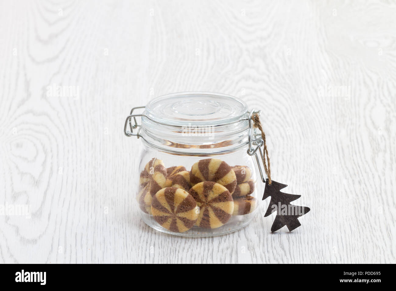 Transparente retro Cookie Jar auf weißen Tisch mit schwarzen und weißen Cookies und sezonda Gefühl Stockfoto