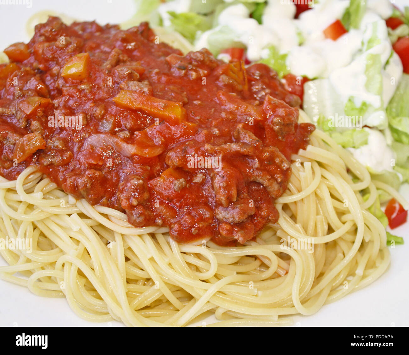Gekochte spaghetti Pasta gekrönt mit einem köstlichen hausgemachten Soße und eine frische Garten Salat garniert mit cremigen Ranch Dressing Stockfoto
