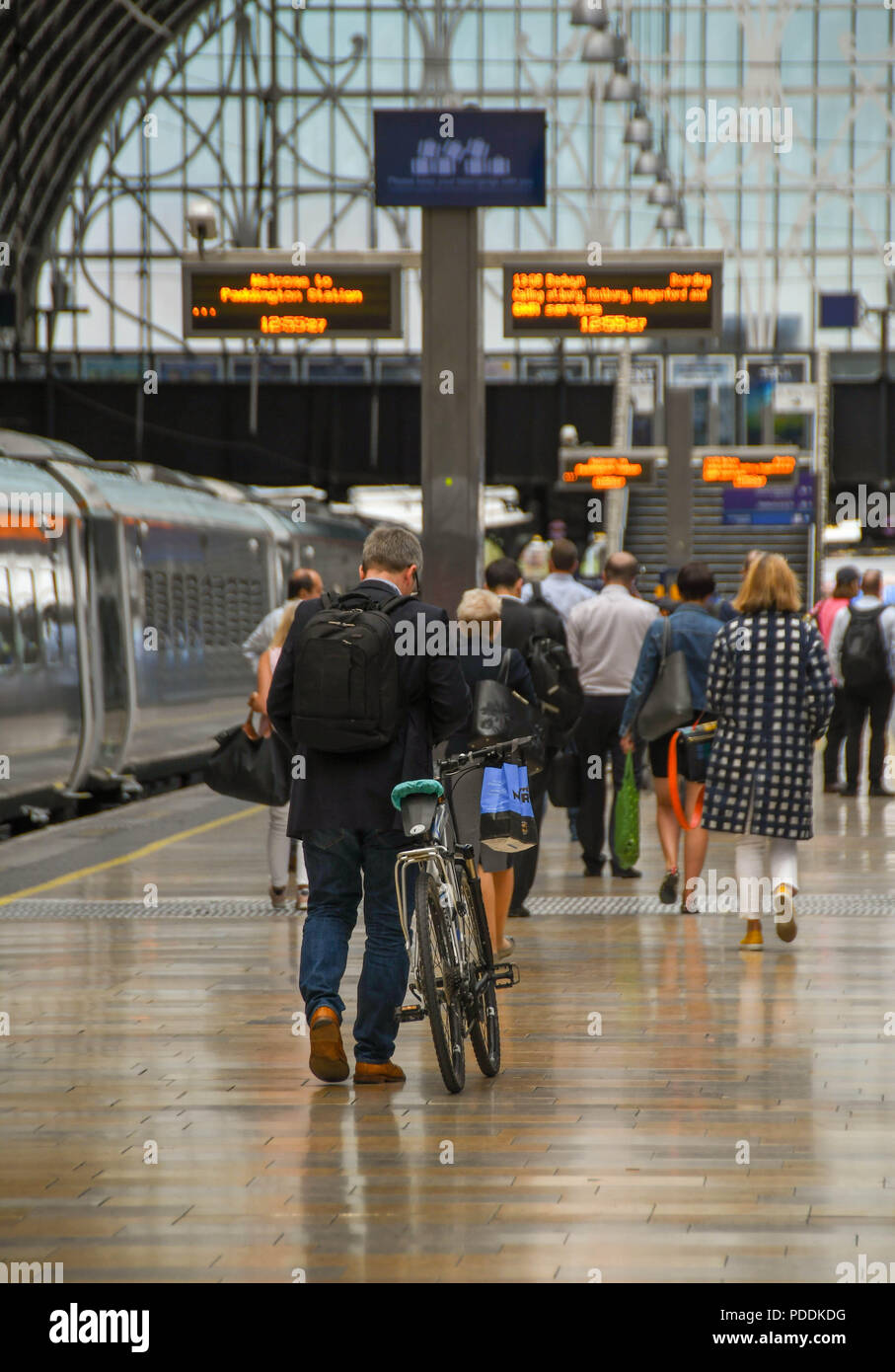 Person WHEELING ein Fahrrad entlang einer Plattform auf London Paddington Station seinen Zug zu bekommen Stockfoto