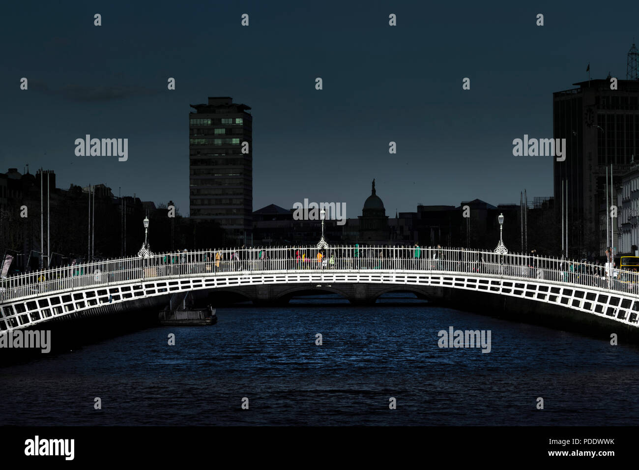 Ha'Penny Bridge durch Licht mit der Stadt Hintergrund im Schatten beleuchtet eine dramatische Wirkung Stockfoto