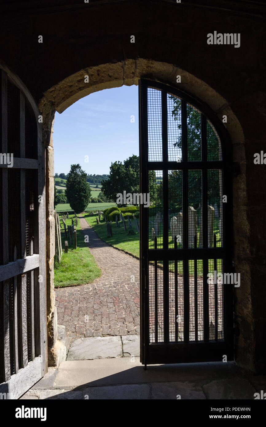 Ein Blick durch eine offene Kirche Tür in die Landschaft dahinter; die Kirche des Hl. Michael, Coxwold, North Yorkshire Stockfoto