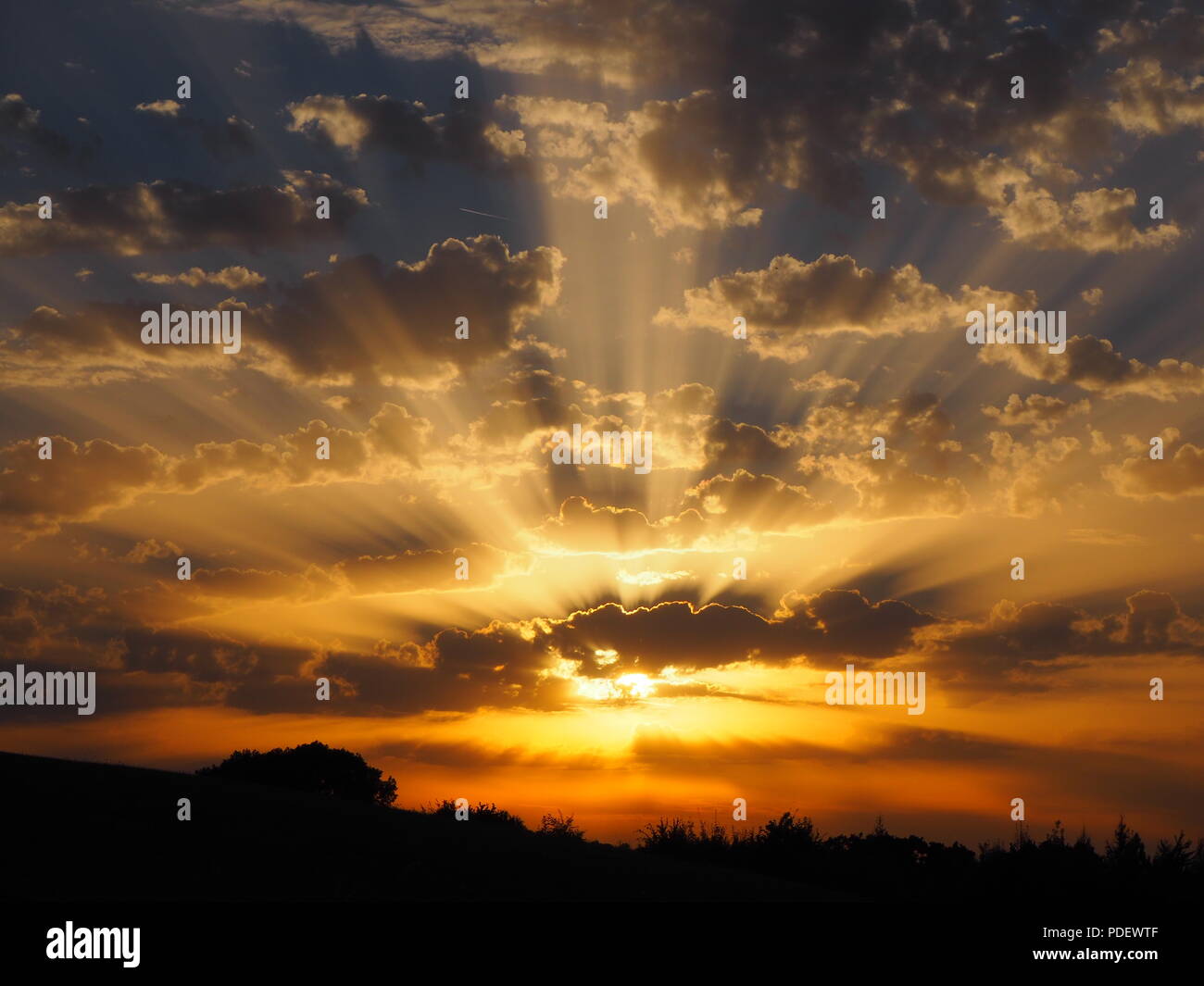 Bunte Himmel mit altocumulus Sonnenuntergang Wolken mit Sonnenstrahlen an Bourne End in der Nähe von Hemel Hempstead, Hertfordshire im späten Sommer gesehen. Stockfoto